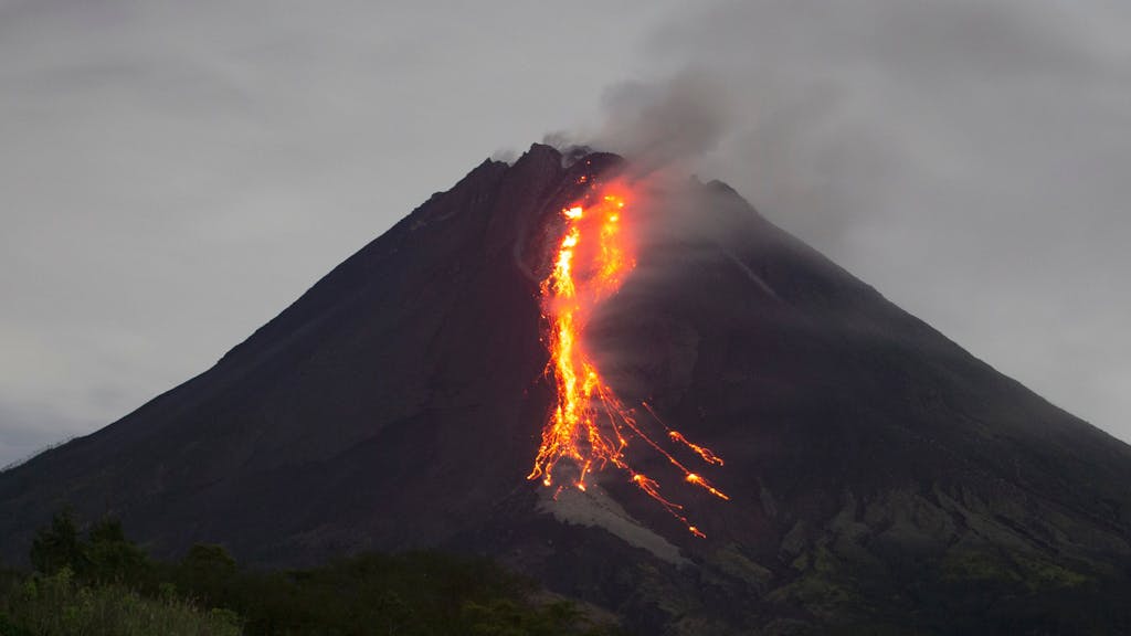 Ein Vulkankrater, aus dem glühende Magma hinausläuft.