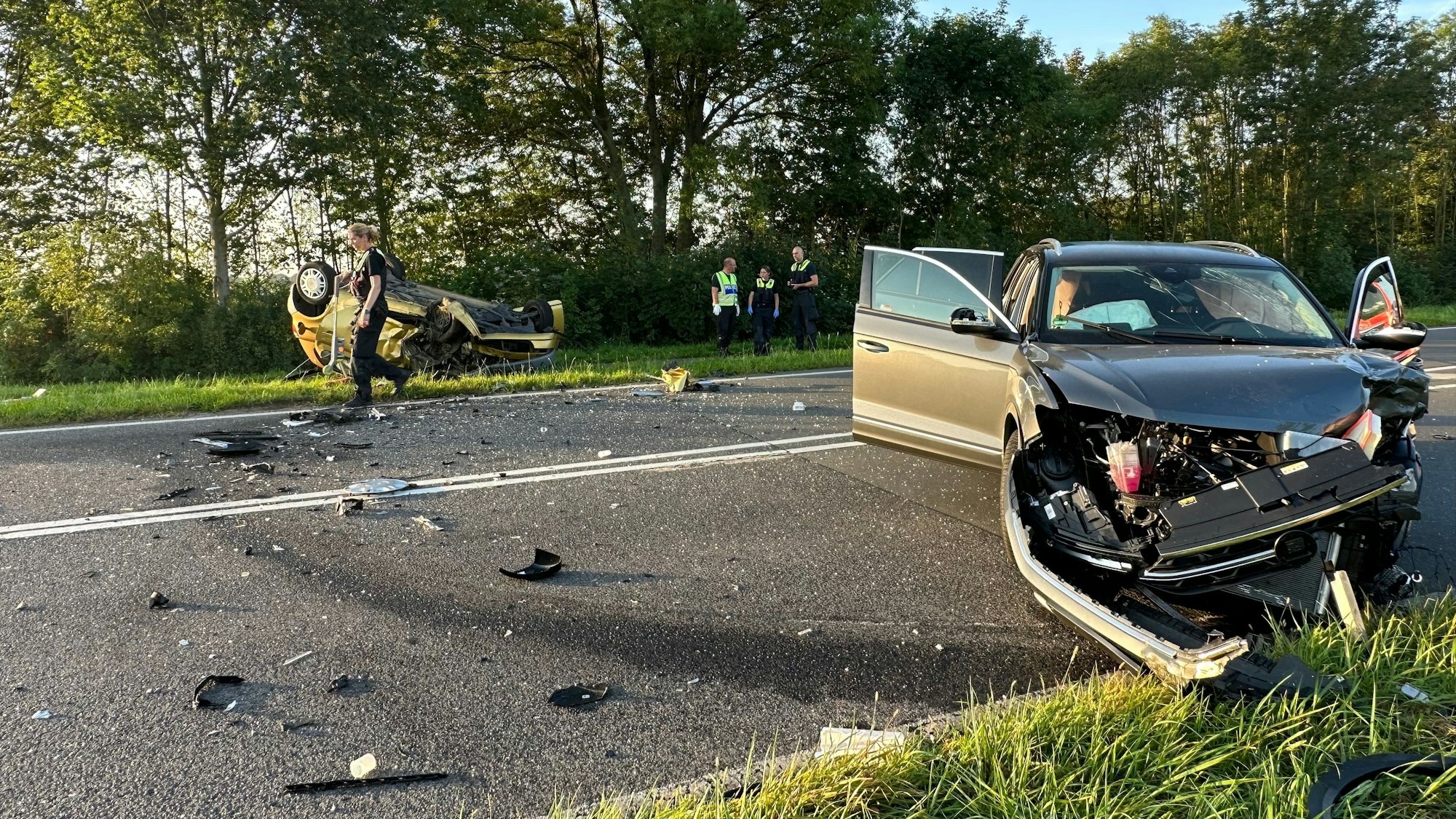 Zwei zerstörte Autos liegen auf einer Straße in Köln nach einem Unfall.
