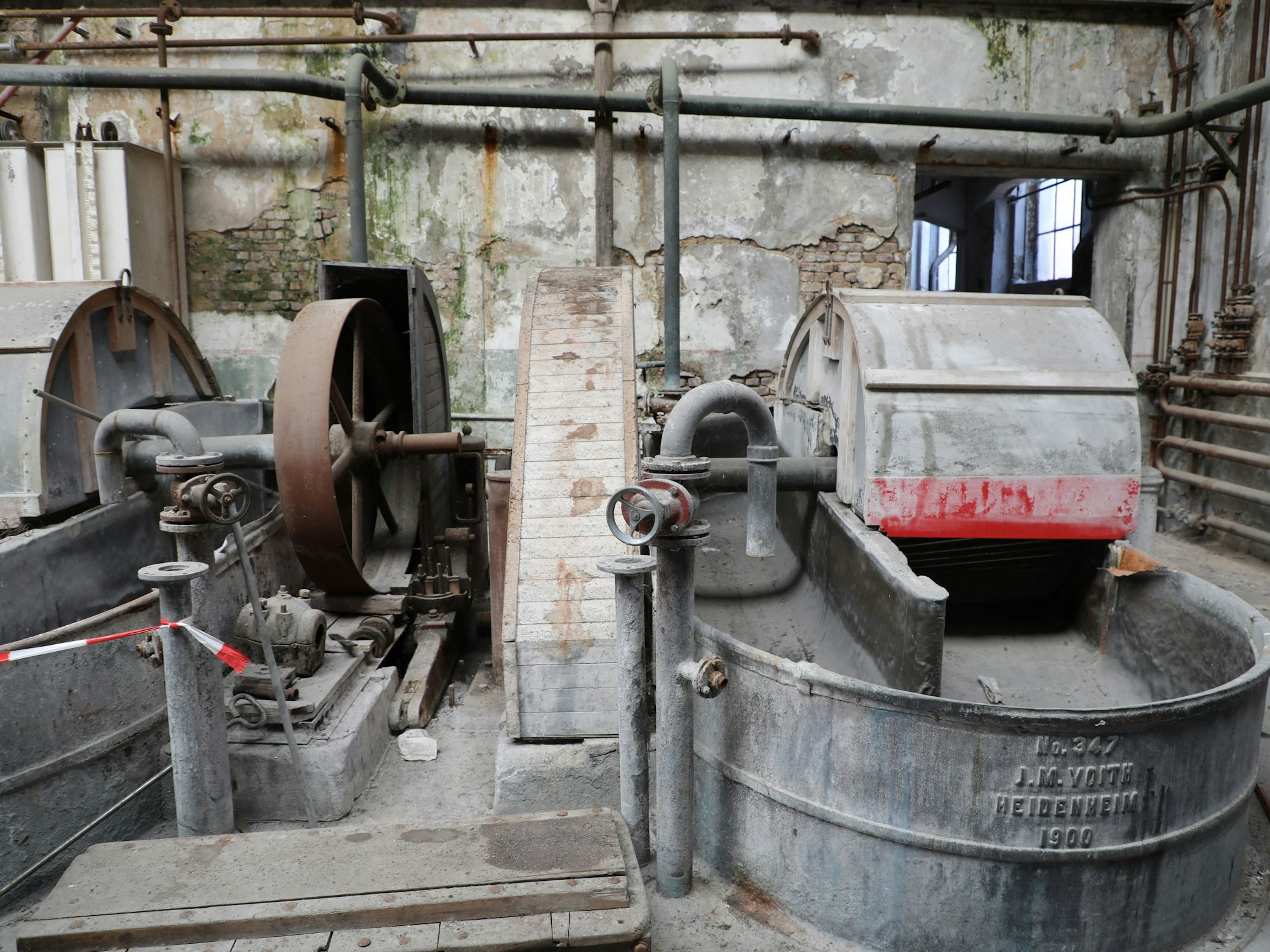 Zwei etwas verstaubte Maschinen stehen in einem alten Fabrikraum.
