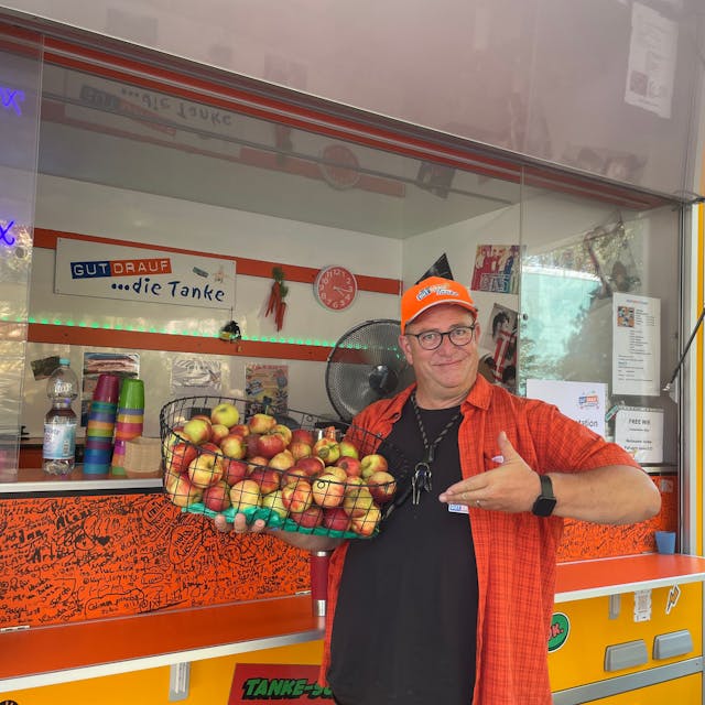 Jürgen Meyer steht mit einem Apfelkorb an dem Verkaufswagen, der Gut drauf-Tanke