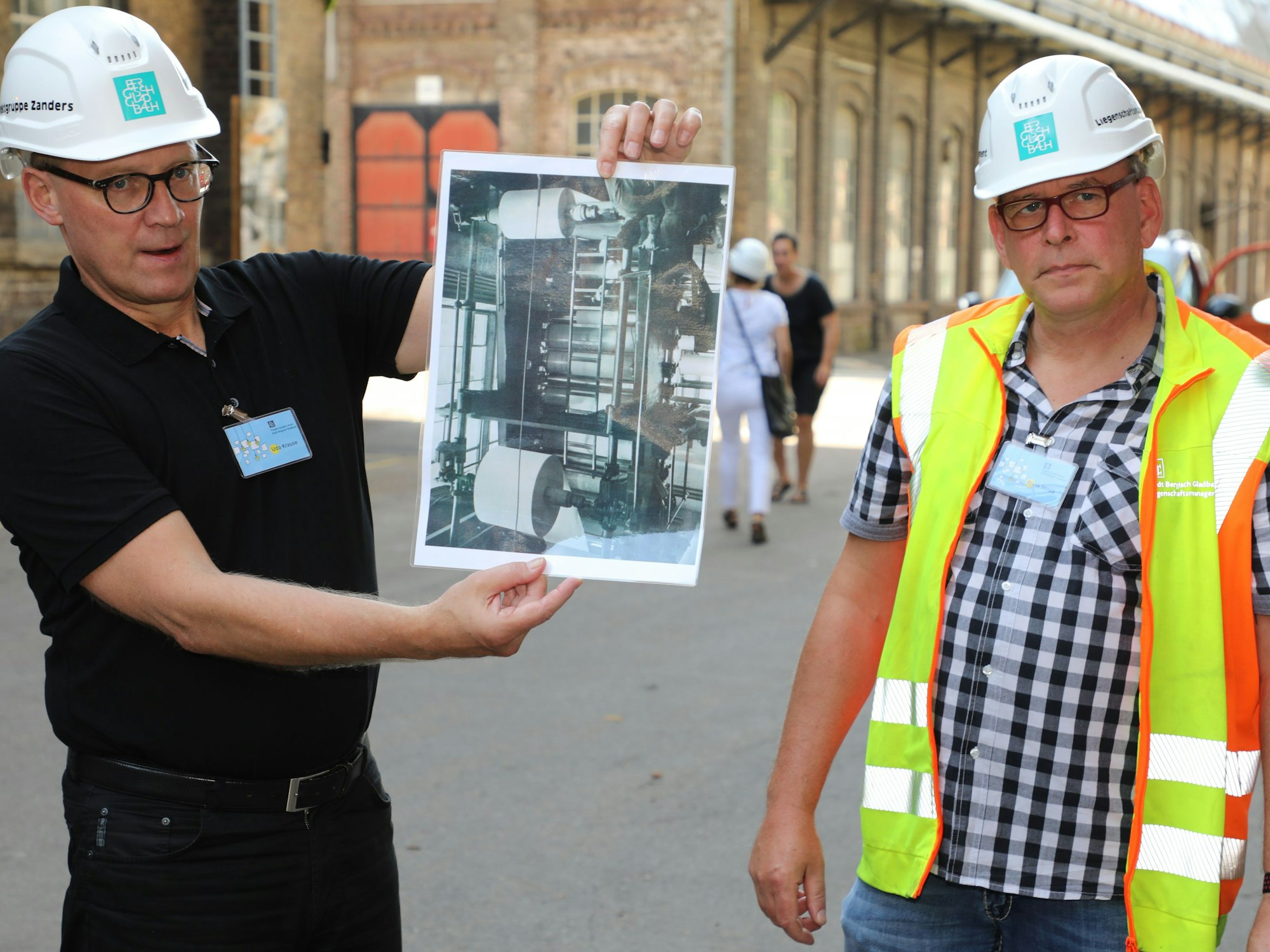 Ex-Zandrianer Frank Stugg (r.) und Udo Krause (Leiter des Zanders-Projektteams) zeigen historische Fotos aus der Papierproduktion bei Zanders.