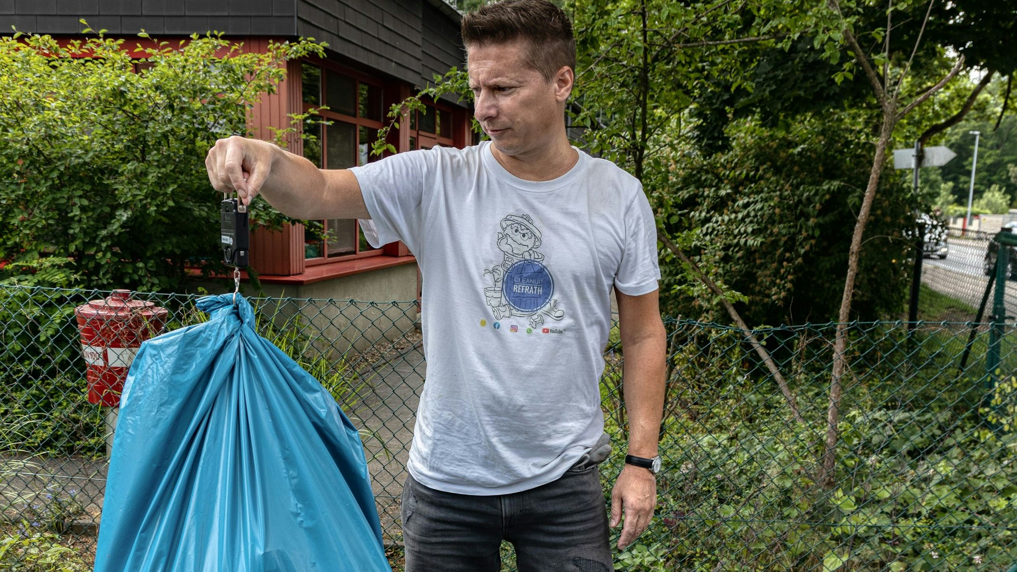 Elmar Zimmermann wiegt einen blauen Müllsack.