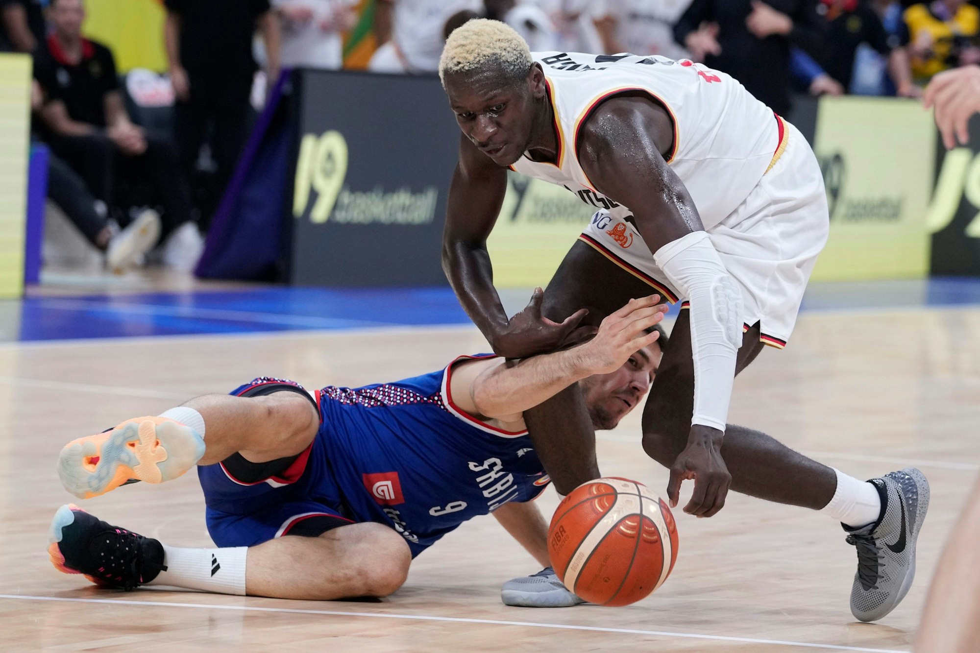 Germany guard Isaac Bonga (0) looks to pick up a loose ball in front of Serbia guard Vanja Marinkovic (9) during the championship game of the Basketball World Cup in Manila, Philippines, Sunday, Sept. 10, 2023. (AP Photo/Michael Conroy)