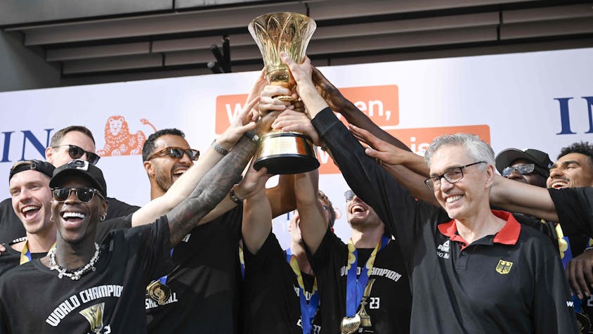 Die deutschen Basketball-Spieler um Dennis Schröder (l.) halten gemeinsam mit Coach Gordon Herbert ihren WM-Pokal hoch.