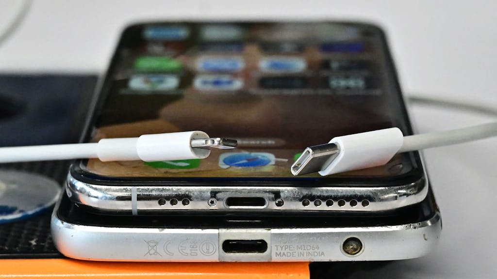 Ein USB-C-Ladegerät (rechts) und ein herkömmliches Apple-Lightning-Ladegerät sind an einem Apple iPhone mit Lightning-Anschluss über einem Android-Telefon mit USB-C-Anschluss zu sehen.