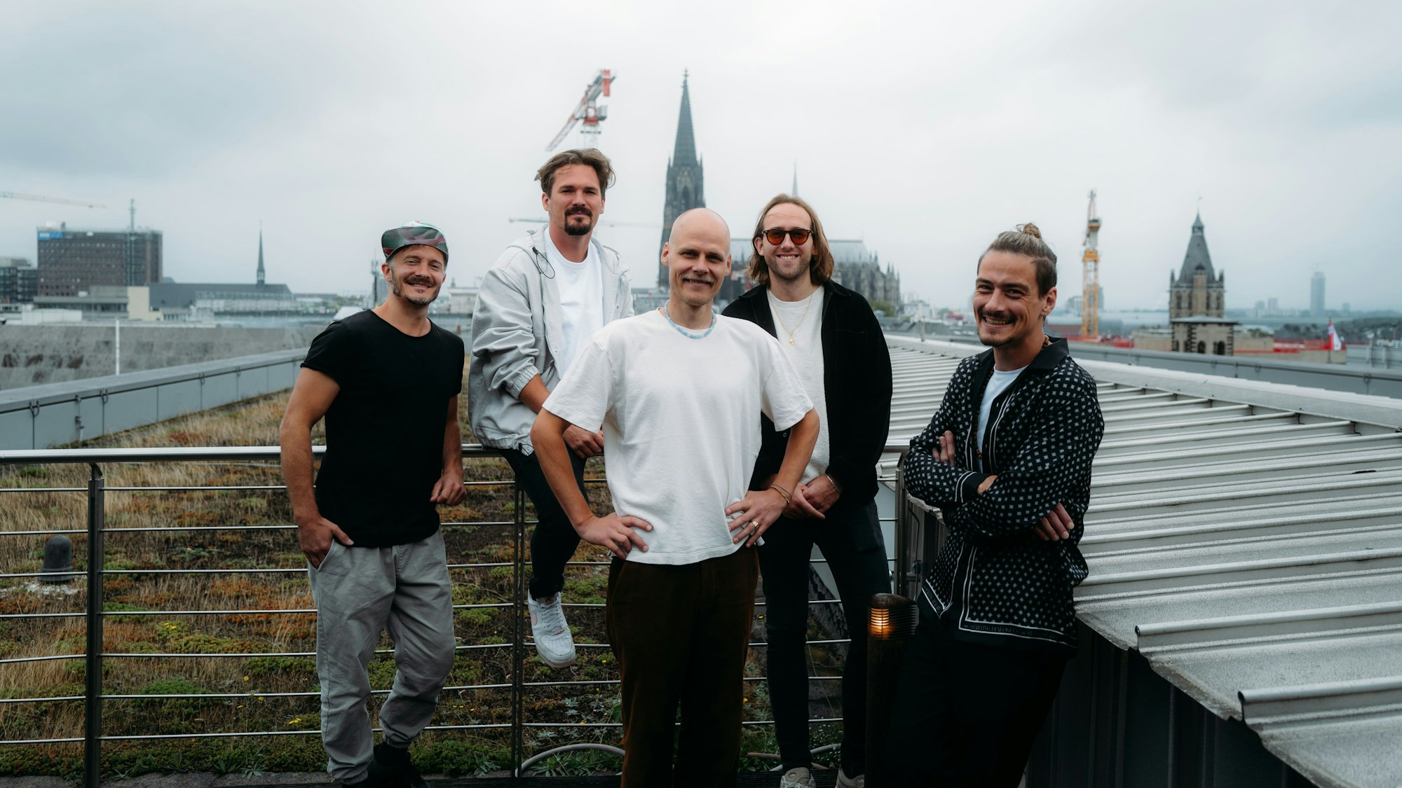 Die fünf Bandmitglieder von Cat Ballou stehen auf einem Dach, im Hintergrund der Kölner Dom.