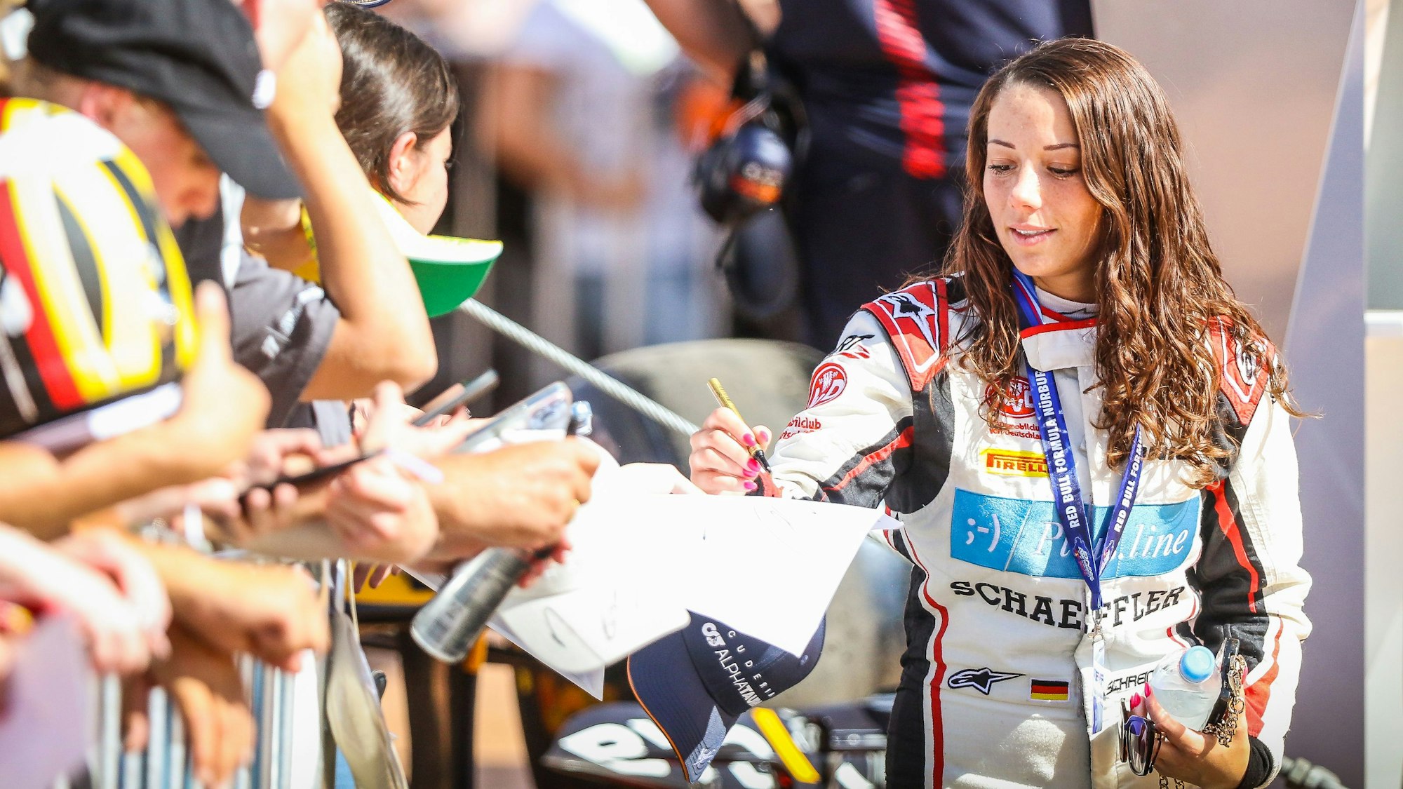 Rennfahrerin Carrie Schreiner schreibt am Nürburgring Autogramme.