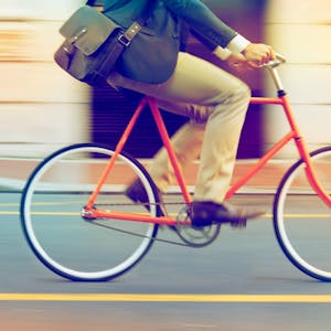 Mann fährt mit Arbeitstasche auf einem Fahrrad Foto: Getty Images/iStockphoto