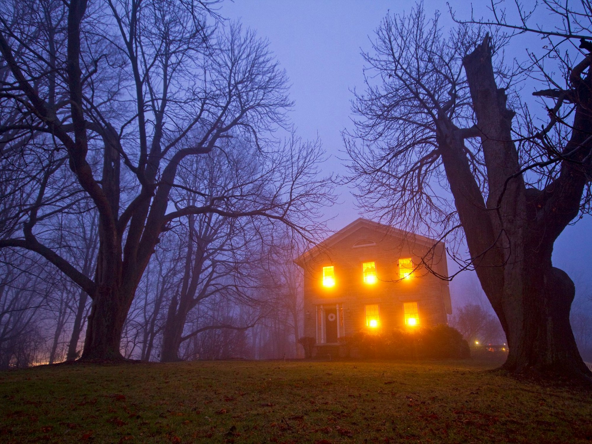 Ein Spukhaus, das bei Nebel beleuchtet ist.
