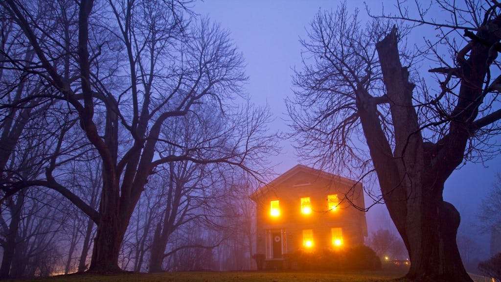Ein Spukhaus, das bei Nebel beleuchtet ist.
