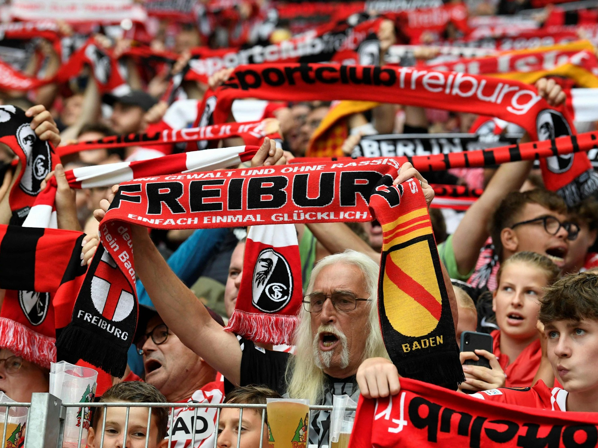 Freiburg-Fans halten ihre Schals hoch.