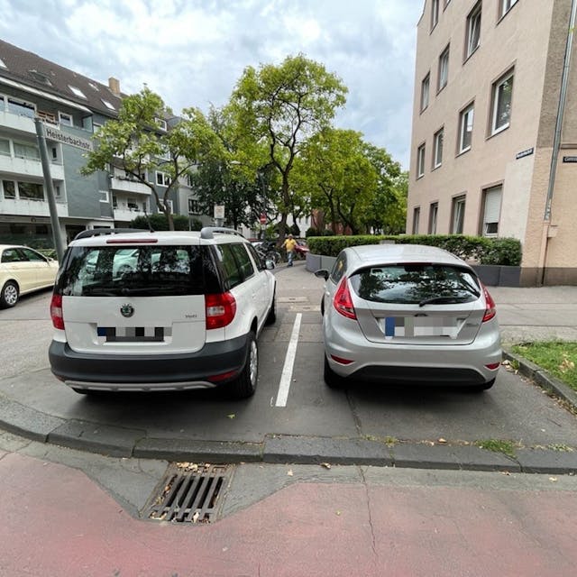 Zwei Autos stehen nebeneinander auf einem Gehweg.