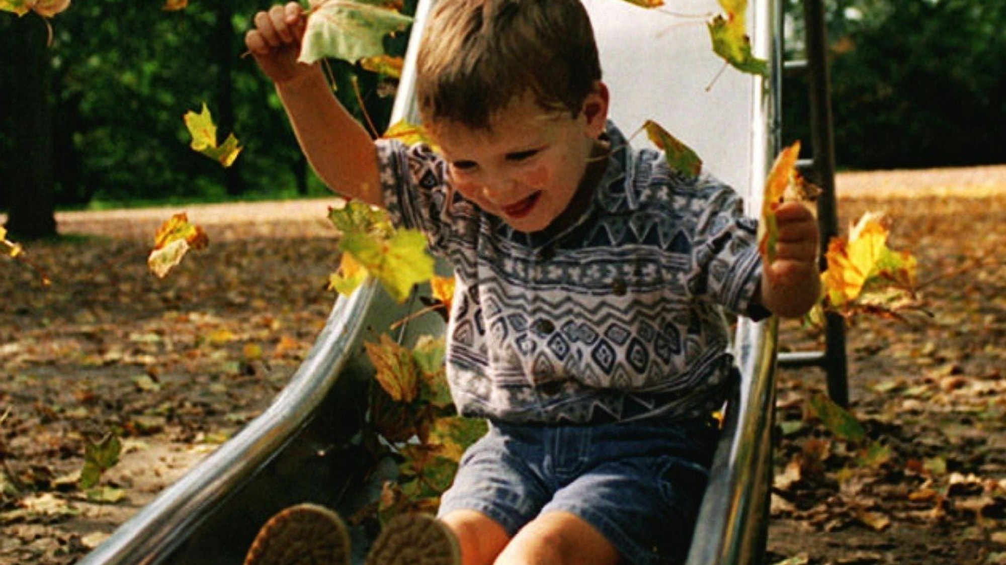 Das Foto zeigt ein lachendes Kind auf einer Rutsche.