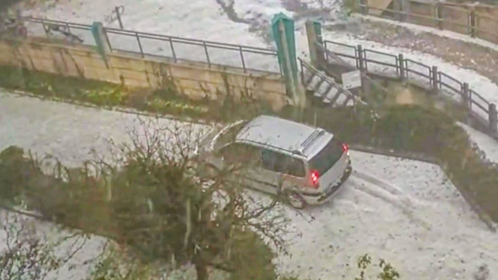 Ein Auto steht inmitten der Hagelmassen in Worms, welche die Stadt in eine Winterlandschaft verwandelte.
