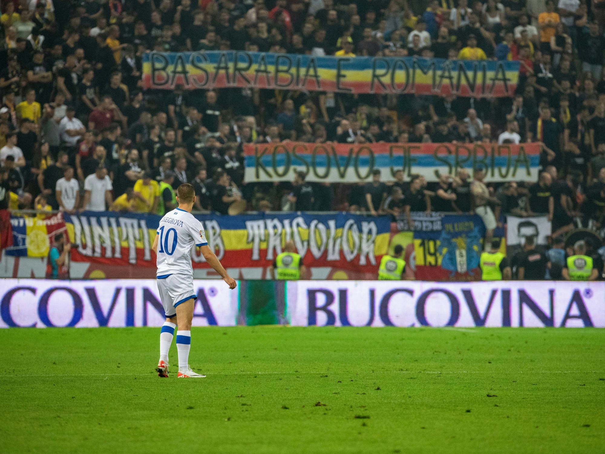Kosovos Edon Zhegrova schaut auf das Plakat, welches rumänischen Fußballfans ausgehangen haben.