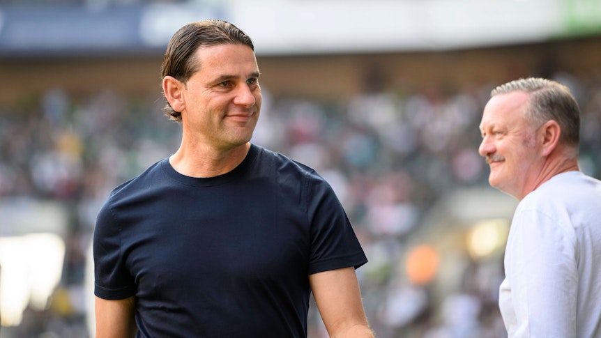 Roland Virkus (r.) lächelt Gerardo Seoane, Trainer von Borussia Mönchengladbach, an.