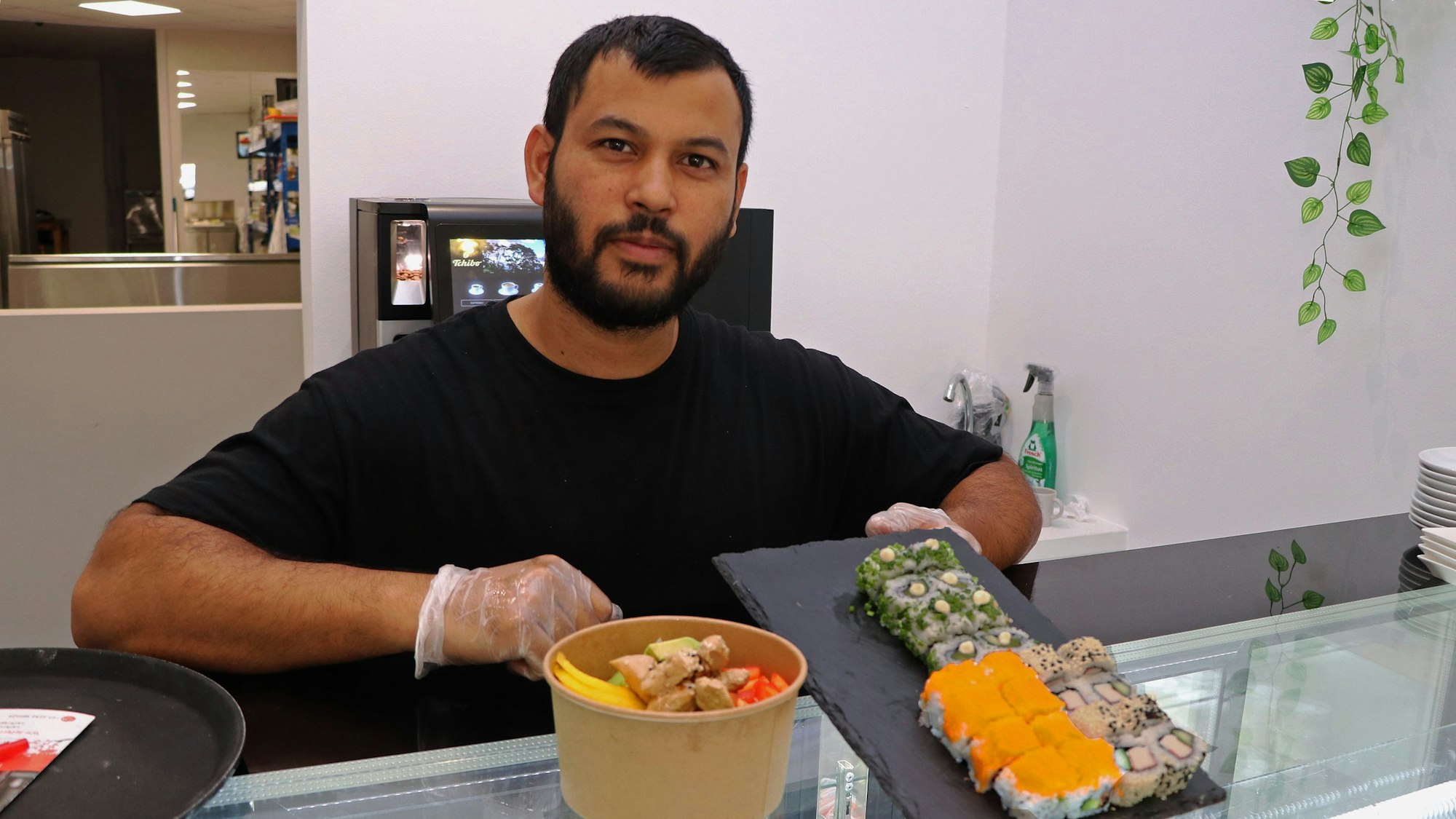 Das Bild zeigt einen Mann, der in seinem Restaurant Sushi und Bowls anbietet.