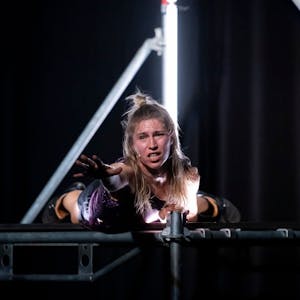 Mette Ingvartsen liegt in „The Dancing Public“ auf einer Bühne aus einem Gerüst und greift mit der Hand ins Leere.&nbsp;