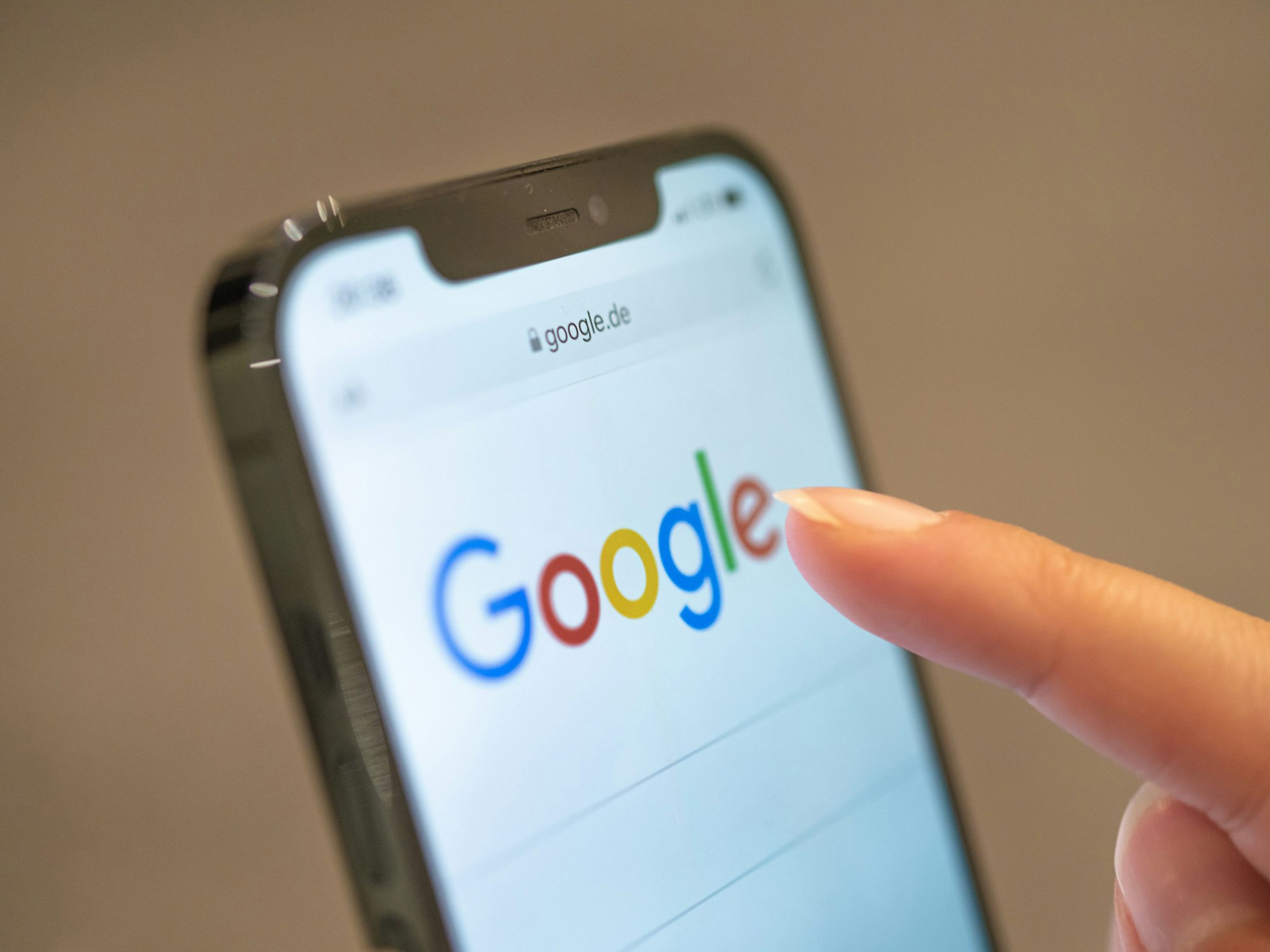 Eine Frau hält ihr Handy in der Hand, auf dem die Google-Seite im Browser zu sehen ist.