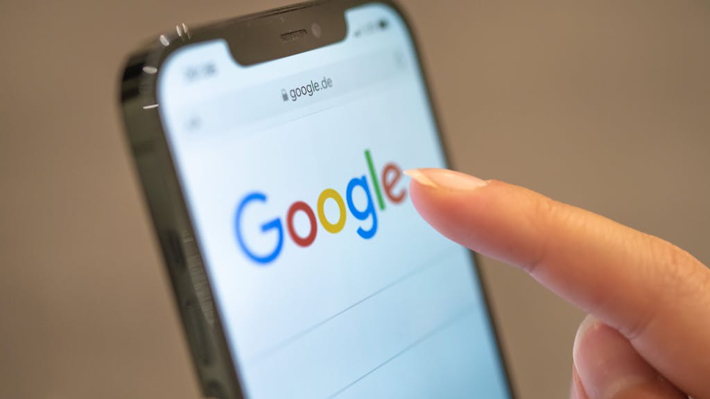 Eine Frau hält ihr Handy in der Hand, auf dem die Google-Seite im Browser zu sehen ist.&nbsp;