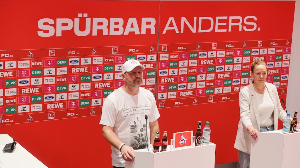 Steffen Baumgart steht vor einer Werbetafel des 1. FC Köln.