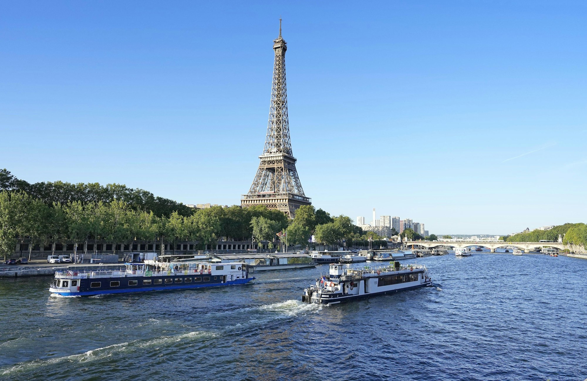Ein Boot und ein Lastkahn fahren vor dem Eiffelturm auf der Seine.