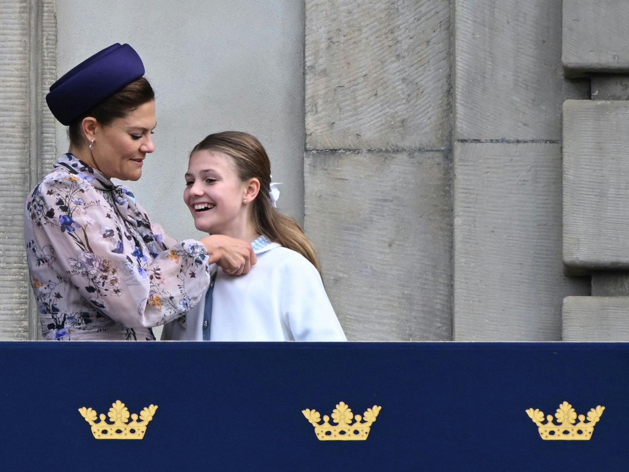 Die schwedische Kronprinzessin Victoria (l) korrigiert der schwedischen Prinzessin Estelle den Kragen, während die schwedische Königsfamilie auf dem Balkon erscheint.