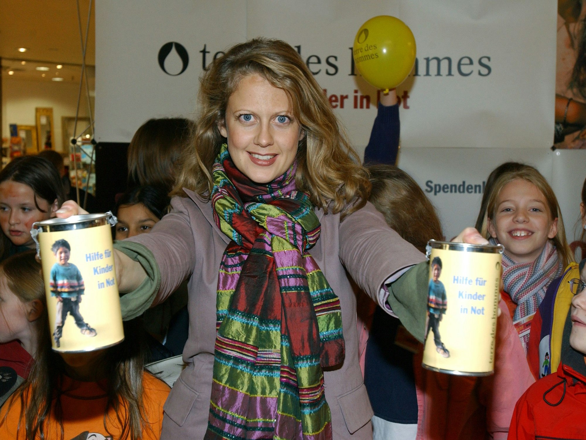 Barbara Schöneberger posiert für ein Foto, hinter ihr eine Gruppe Kinder.