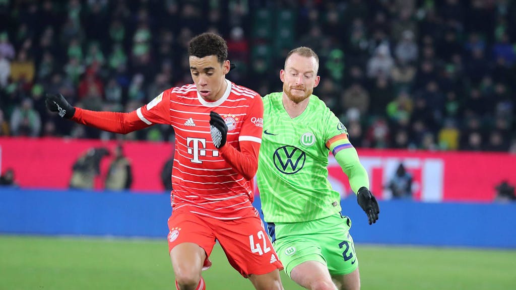 Jamal Musiala vom FC Bayern München führt den Ball, Maximilian Arnold vom VfL Wolfsburg rennt hinterher.