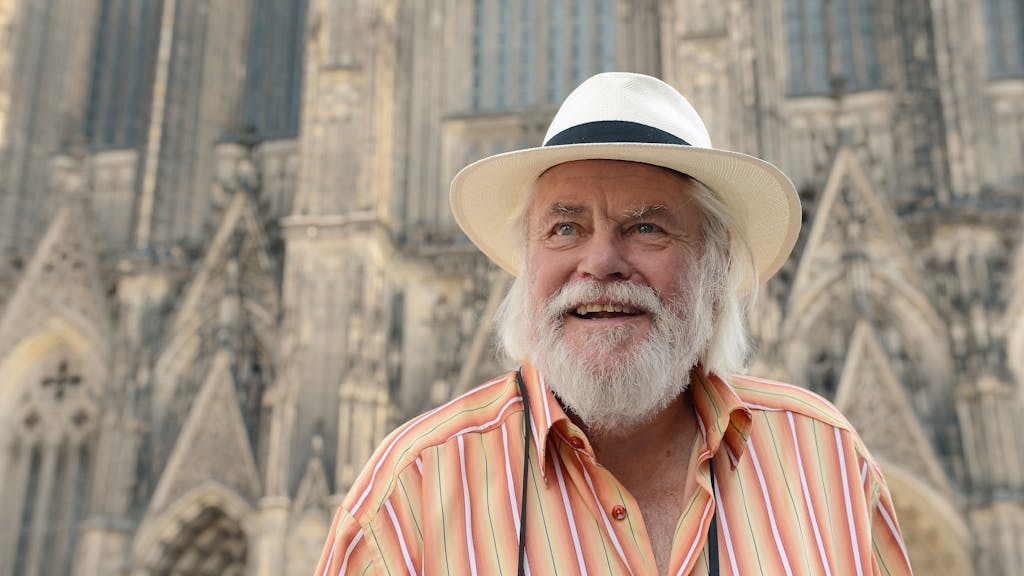 Sänger „King Size Dick“ steht mit Hut auf dem Kopf vor dem Kölner Dom.