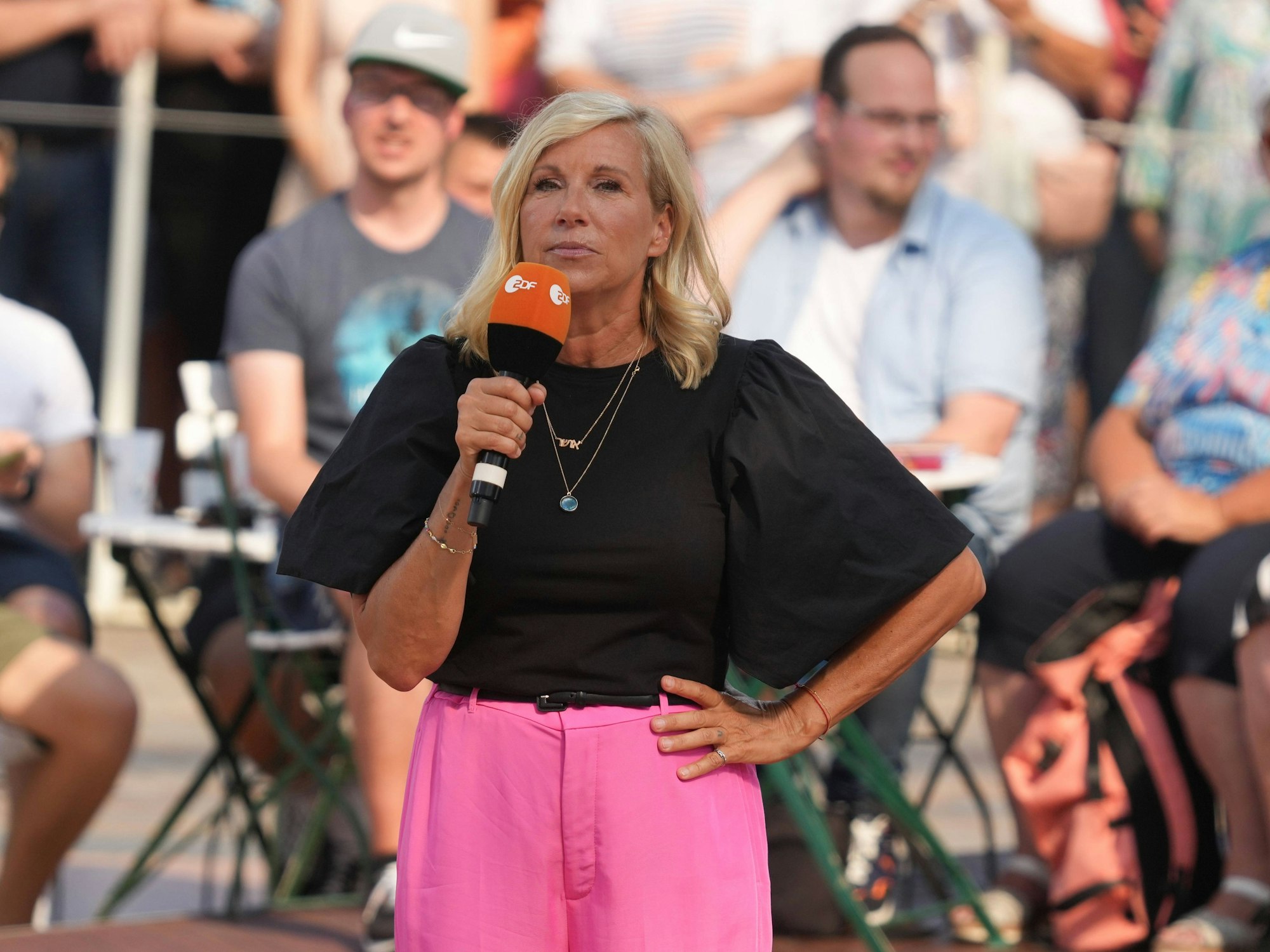 „Fernsehgarten“-Moderatorin Andrea Kiewel steht mit einem Mikrofon in der Hand auf der Bühne.