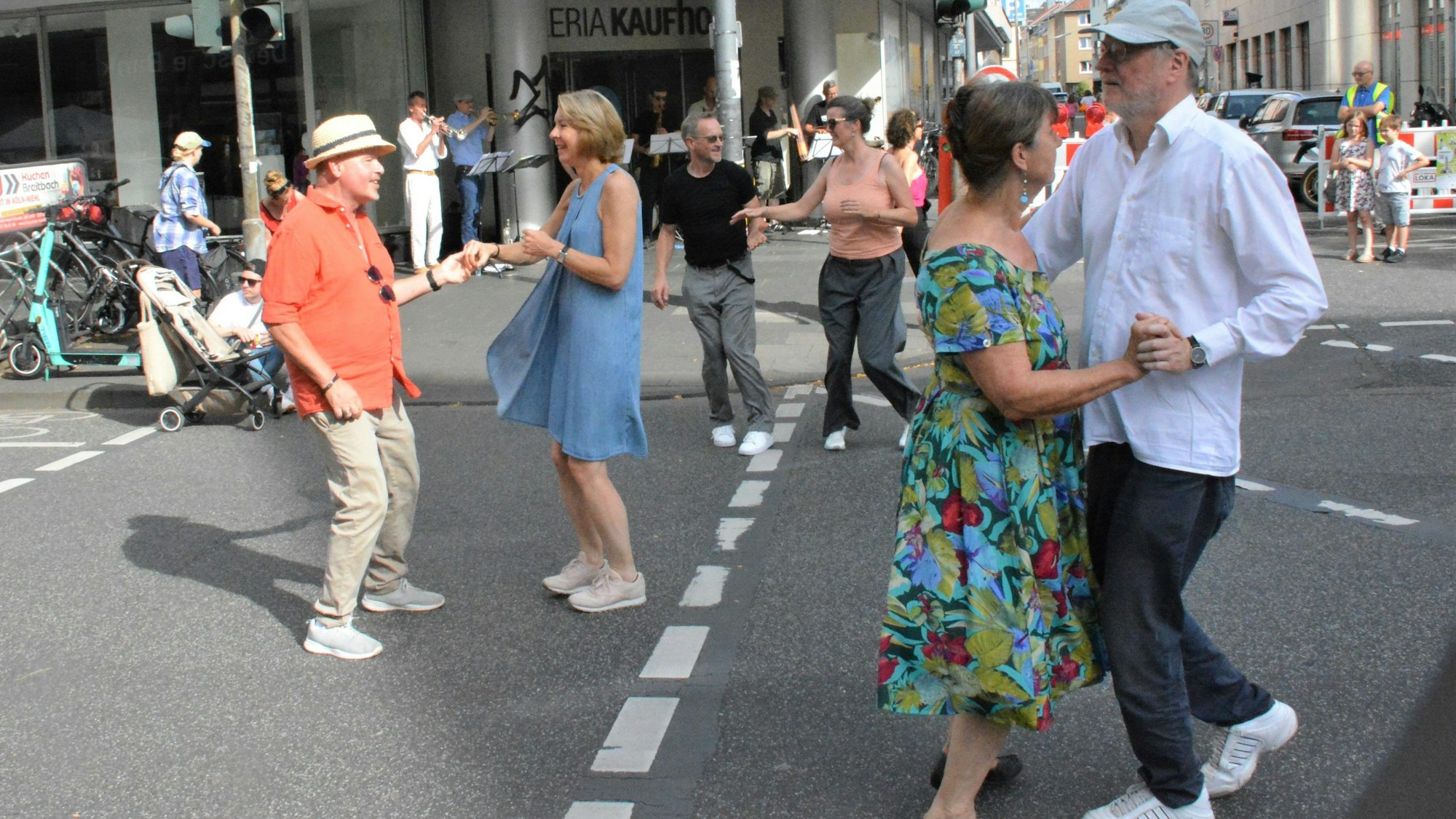 Drei Paare tanzen auf der Neusser Straße. Im Hintergrund steht eine Band.