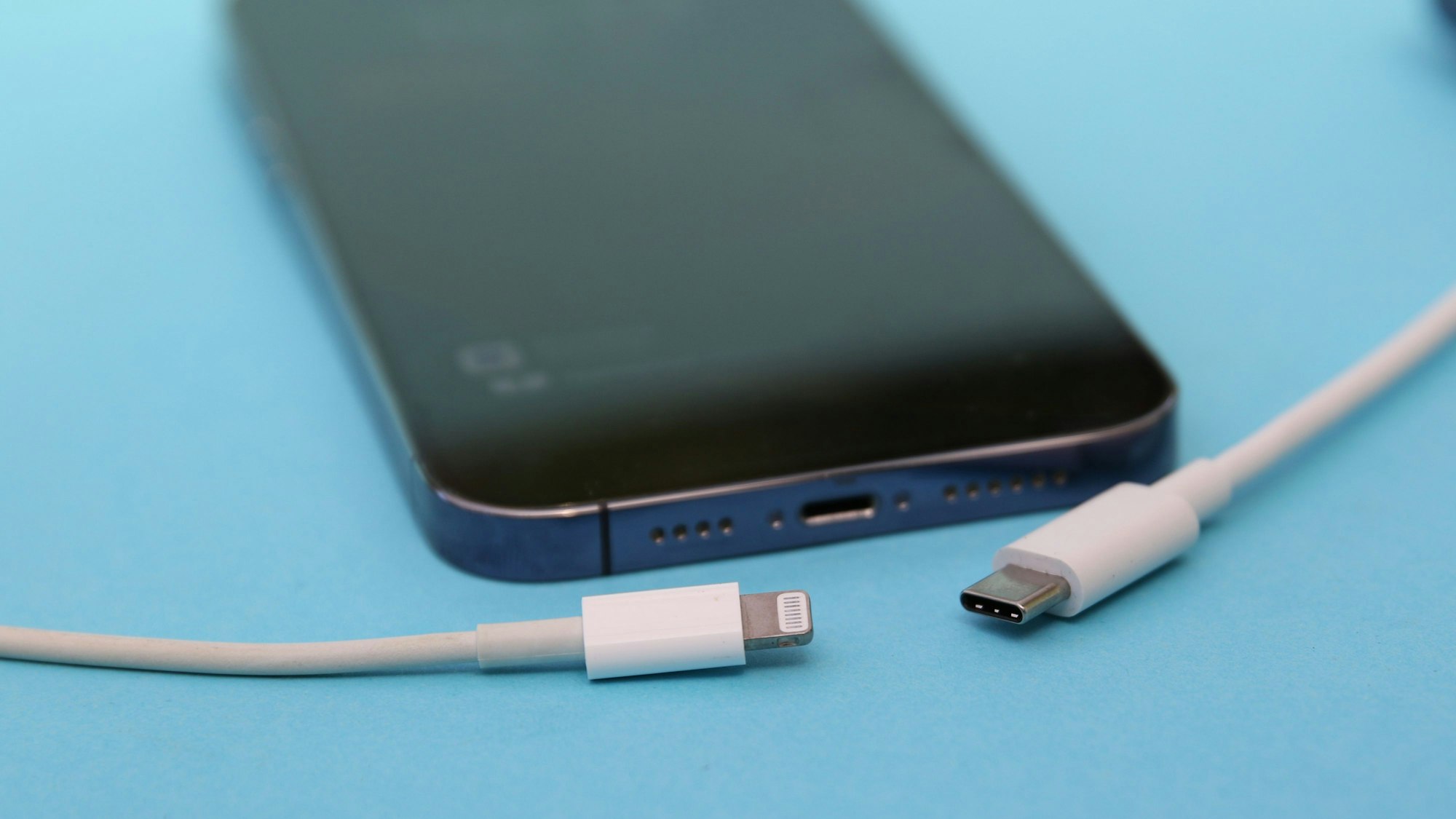 Ein iPhone 14 Pro mit einem Lightning-Kabel (links) und einem USB-C-Kabel (rechts).