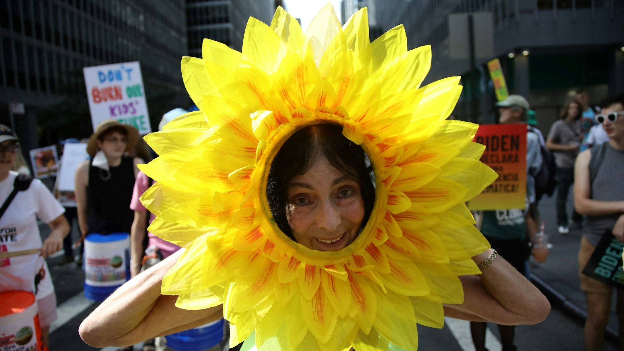 Eine Frau geht als Sonnenblume kostümiert bei einer Demonstration auf einer Straße New Yorks mit.