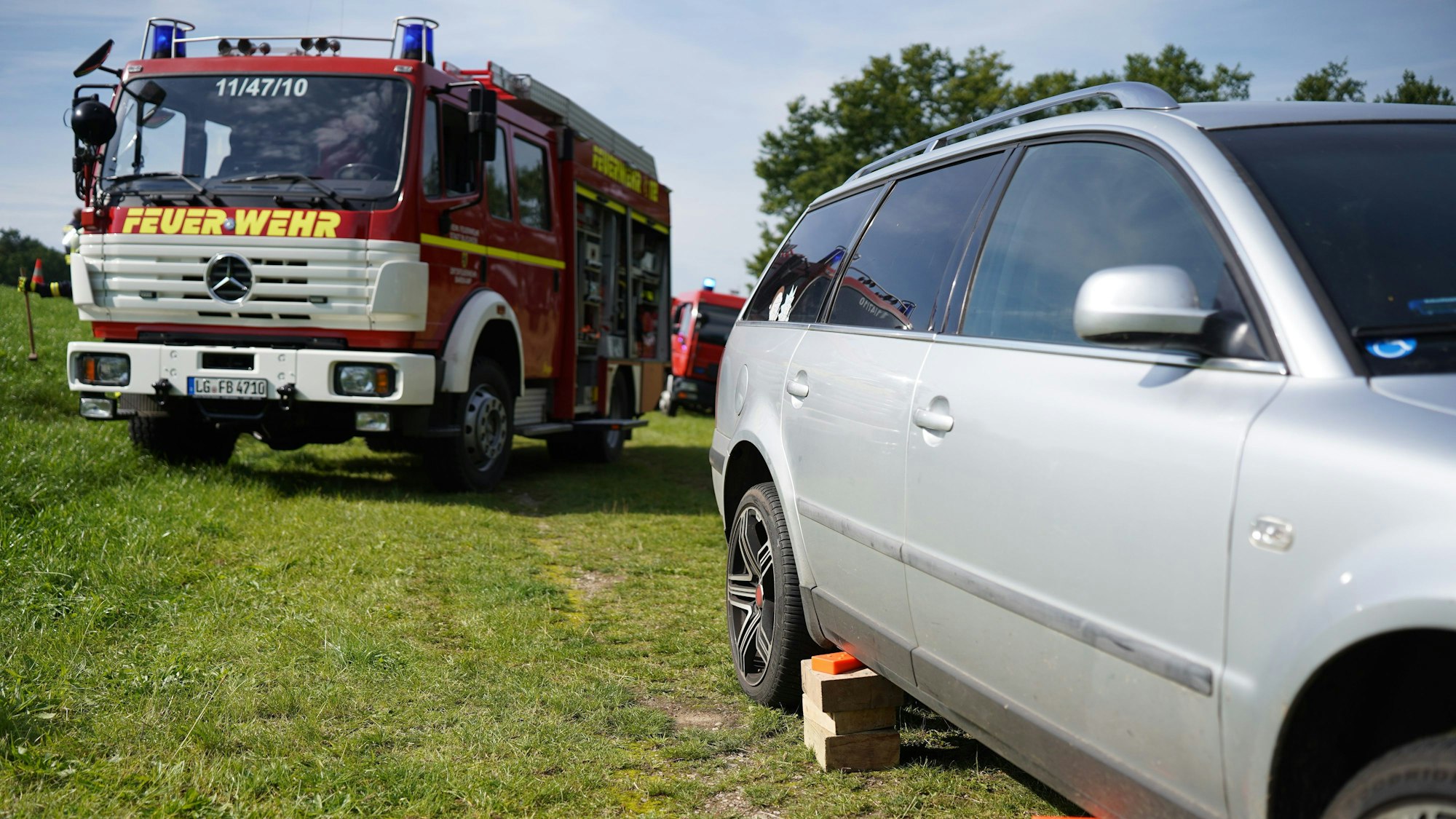 Der Unfallwagen, ein silberner Kombi, und ein Fahrzeug der Feuerwehr stehen am Unfallort.