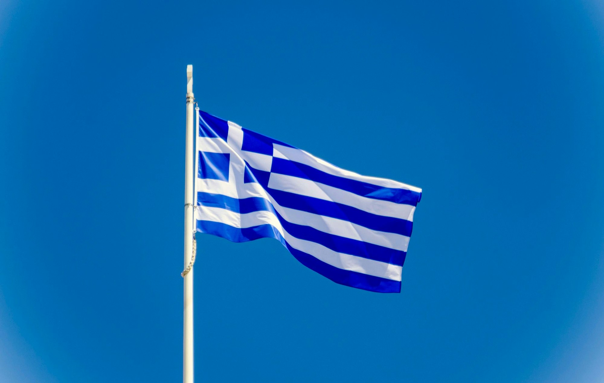 Die griechische Flagge weht an einem Fahnenmast.