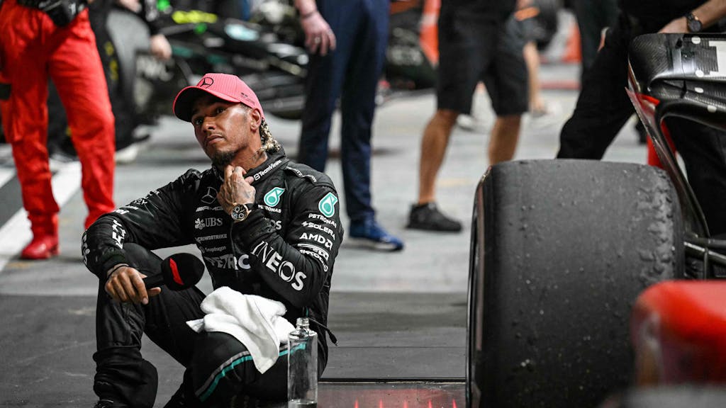 Lewis Hamilton sitzt mit einer Flasche Wasser an seinem Formel-1-Boliden.