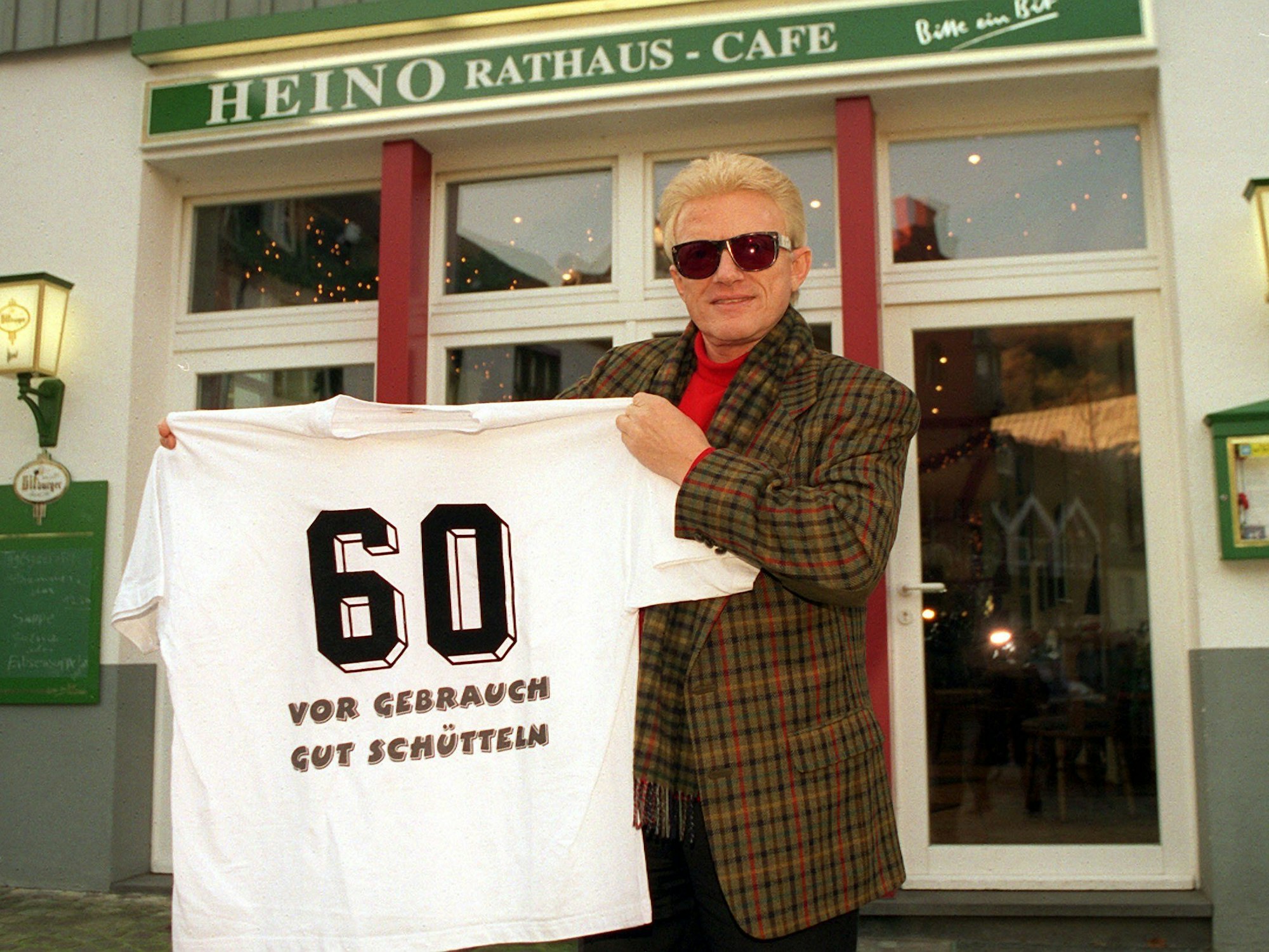Vor seinem Rathaus-Cafe in Bad Münstereifel zeigt Heino ein T-Shirt mit der Aufschrift „60 vor Gebrauch schütteln“.