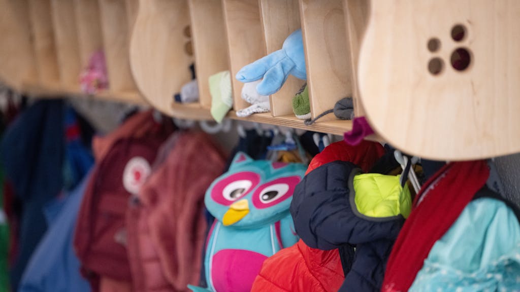 Taschen und Jacken hängen in einem Kindergarten an der Gaderobe.