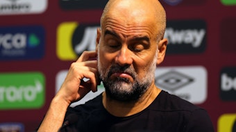 Pep Guardiola kratzt sich bei einer Pressekonferenz am 16. September 2023 am rechten Ohr.