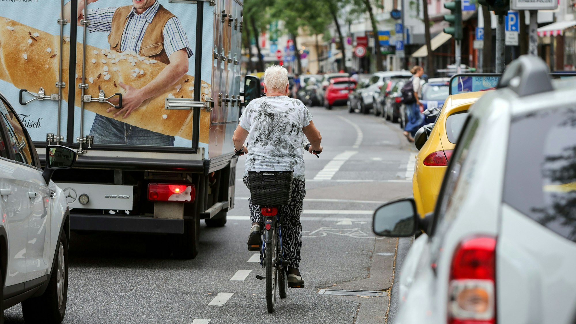 Eine Fahrradfahrerin fährt auf einem Radweg neben einem LKW entlang.