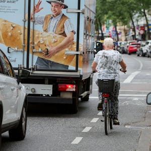 Eine Fahrradfahrerin fährt auf einem Radweg neben einem LKW entlang.