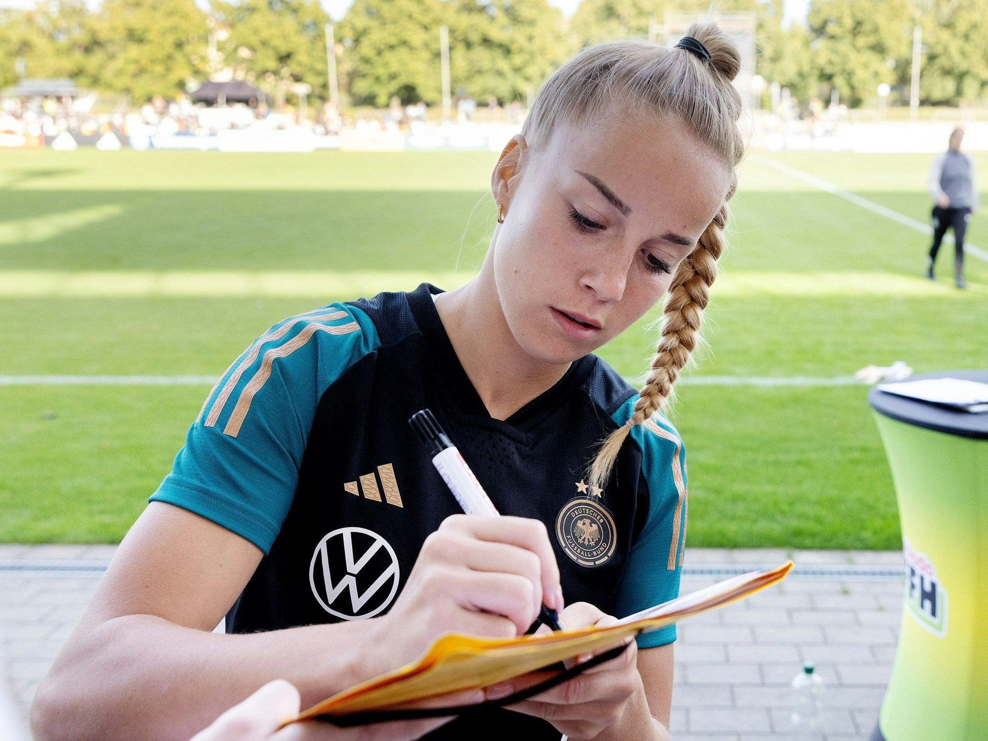 Giulia Gwinn schreibt am Rande des DFB-Trainings Autogramme.