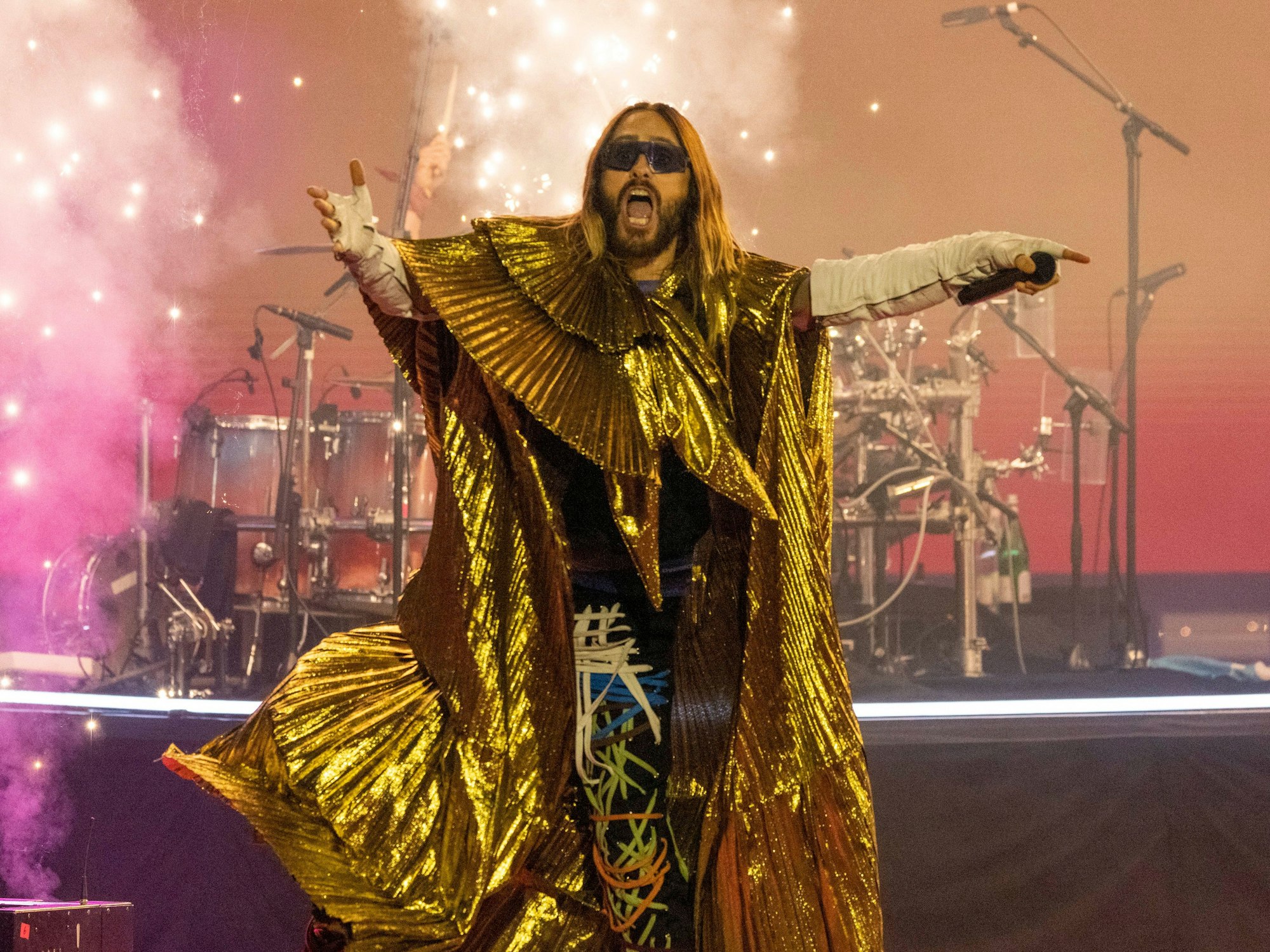 Jared Leto steht in einem goldenen Outfit auf der Bühne und singt.