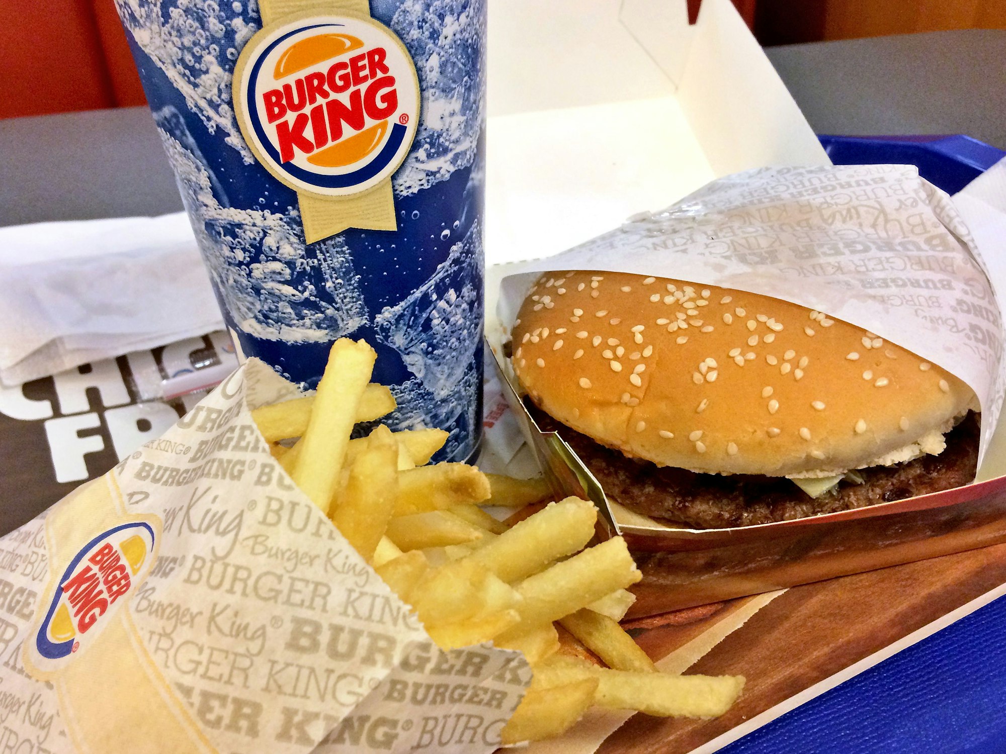 Ein Burger liegt mit Pommes und Getränk bei Burger King auf einem Tisch.