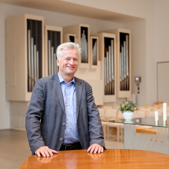 Ansichten der neuen evangelischen Erlöserkirche in Köln Weidenpesch. Pfarrer Markus Zimmermann ist vor dem gläsernen Altar in einem lichten Raum zu sehen.&nbsp;
