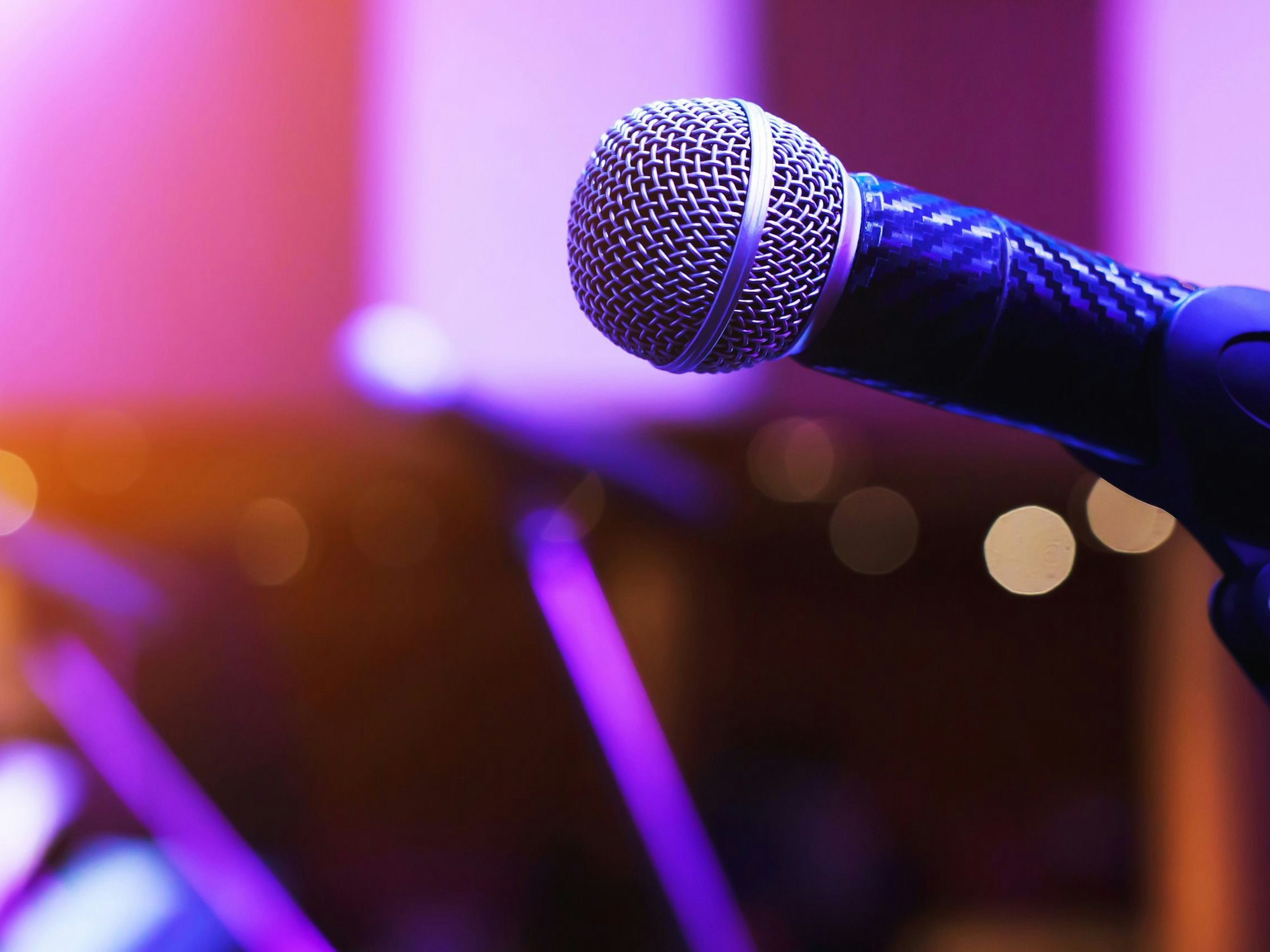 Nahaufnahme eines Mikrofons auf der Bühne eines Konzertsaals oder Konferenzraums.