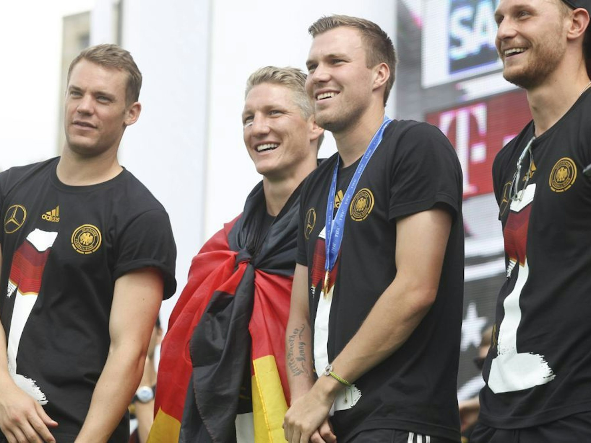 Manuel Neuer, Bastian Schweinsteiger, Kevin Großkreutz und Shkodran Mustafi: Die deutsche Nationalmannschaft feiert den WM-Sieg auf der Fanmeile vor dem Brandenburger Tor.