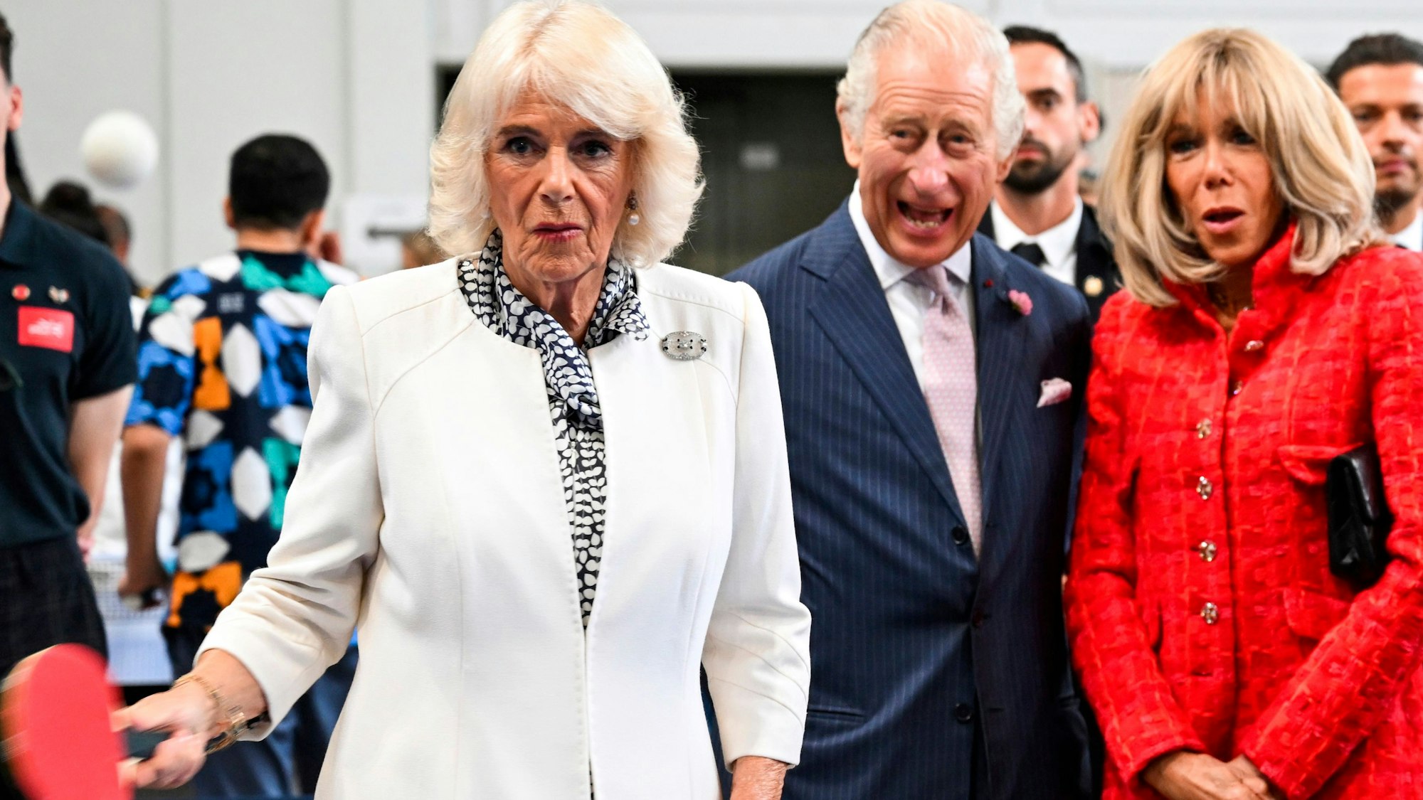 Königin Camilla (l) von Großbritannien spielt im Rahmen des Besuchs in einer Sporthalle Tischtennis, während König Charles III. und Brigitte Macron, Ehefrau des Präsidenten von Frankreich, zuschauen.