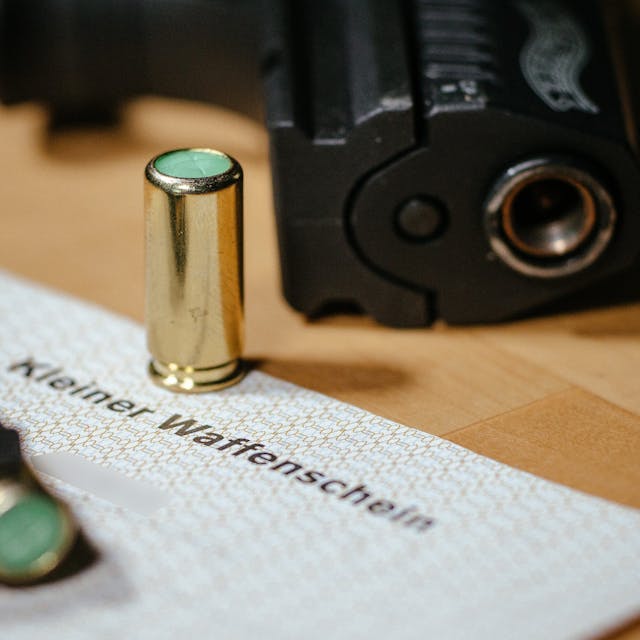 Ein kleiner Waffenschein liegt zwischen einer Schreckschuss-Pistole «Walther P22», einem Magazin und einer Platzpatrone.